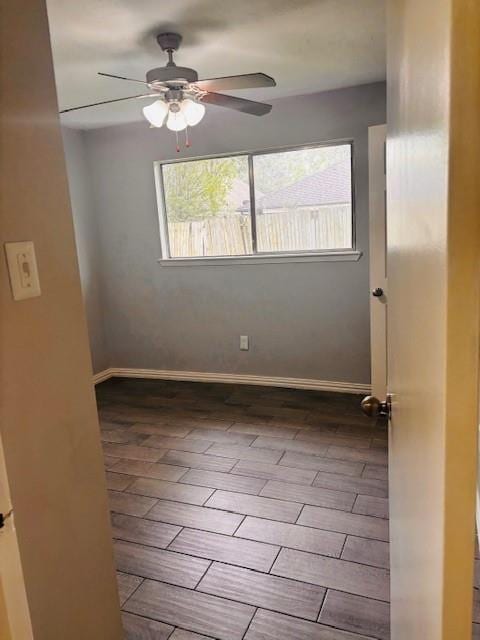 spare room featuring a wealth of natural light, wood finished floors, a ceiling fan, and baseboards
