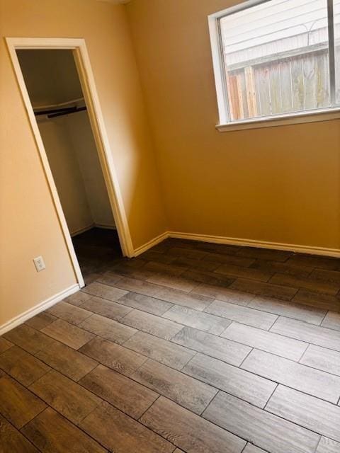 unfurnished bedroom featuring a closet, wood finished floors, and baseboards