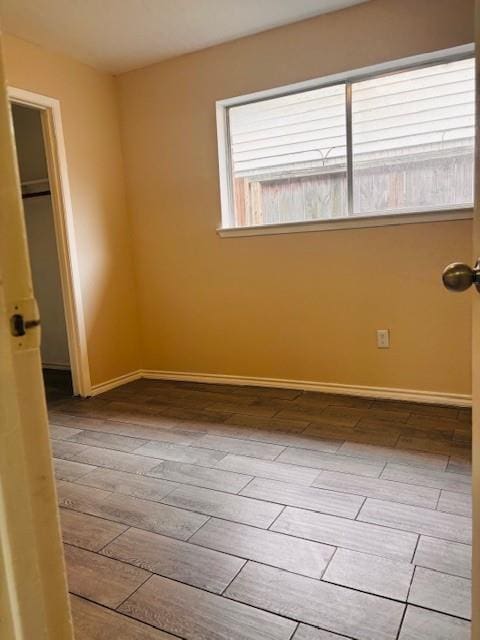 unfurnished bedroom with a closet, wood finished floors, and baseboards