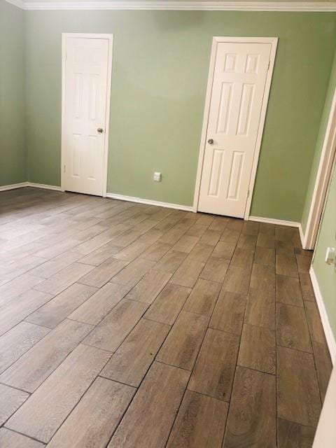 unfurnished bedroom with baseboards, dark wood-style flooring, and crown molding