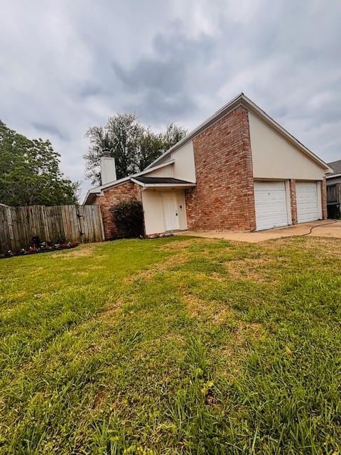 view of side of property featuring brick siding, a yard, a chimney, and fence