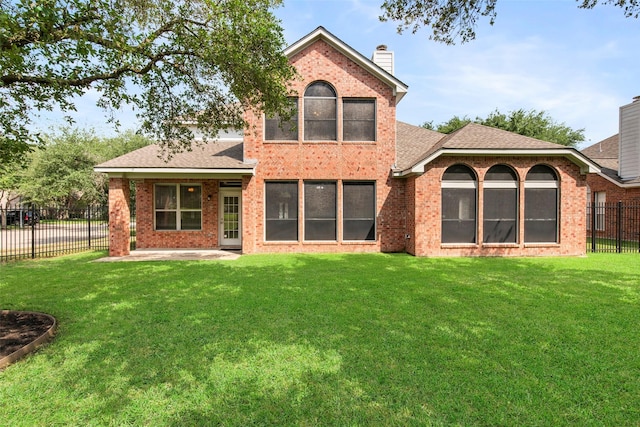 back of property with a patio, a chimney, fence, a yard, and brick siding