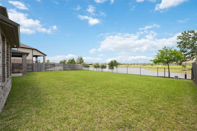 view of yard with a water view and a fenced backyard