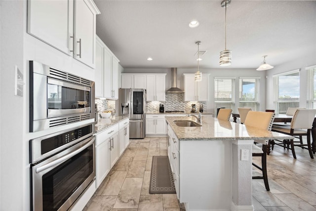 kitchen with a sink, tasteful backsplash, a breakfast bar area, white cabinets, and appliances with stainless steel finishes