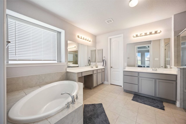 full bath with two vanities, a bath, a sink, visible vents, and a stall shower
