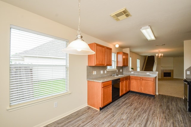 kitchen featuring visible vents, light countertops, dishwasher, a peninsula, and a notable chandelier