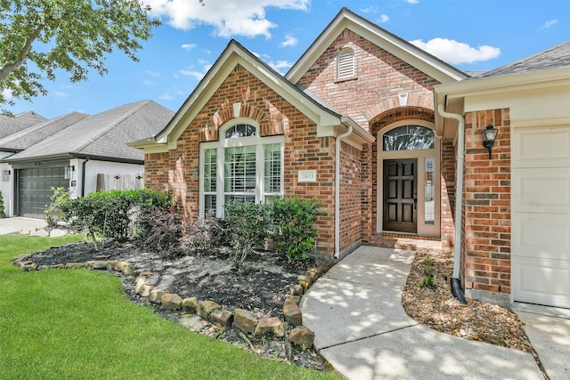 7403 Hickory Canyon Ct, Humble, TX 77396 - view of exterior entry with a yard, a shingled roof, brick siding, and a garage