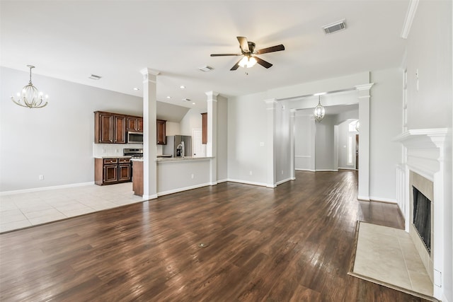 7403 Hickory Canyon Ct, Humble, TX 77396 - unfurnished living room featuring a tiled fireplace, visible vents, ceiling fan with notable chandelier, and light wood-style floors