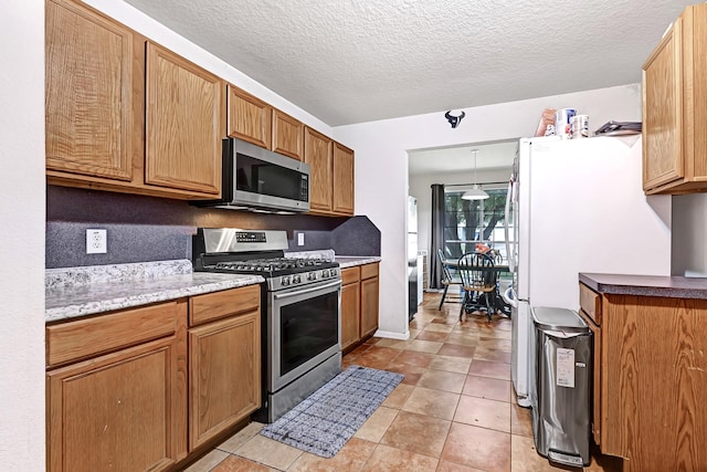 kitchen with light stone countertops, light tile patterned floors, a textured ceiling, and appliances with stainless steel finishes