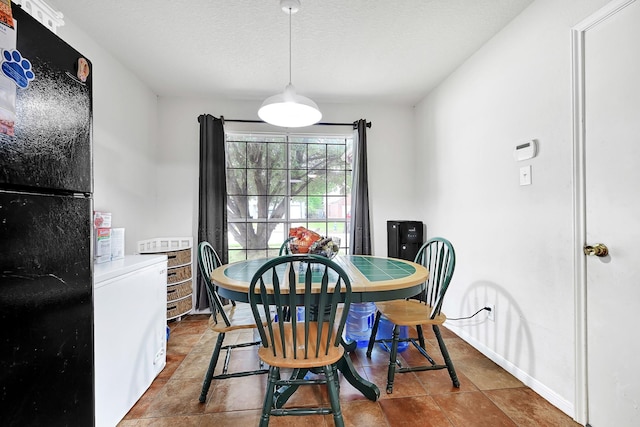 dining space featuring baseboards, tile patterned floors, and a textured ceiling