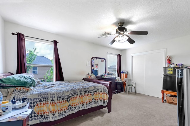bedroom with a textured ceiling, light colored carpet, ceiling fan, visible vents, and a closet