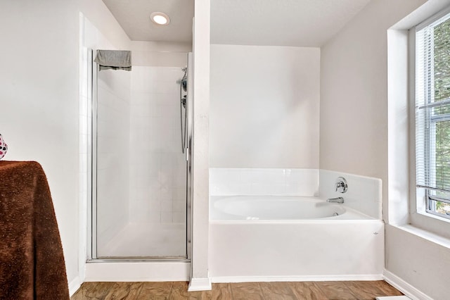 bathroom featuring baseboards, a bath, a shower stall, and a healthy amount of sunlight