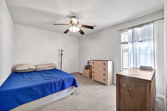 bedroom with visible vents, a ceiling fan, and light carpet