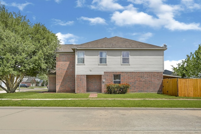 traditional-style home featuring brick siding, fence, and a front yard