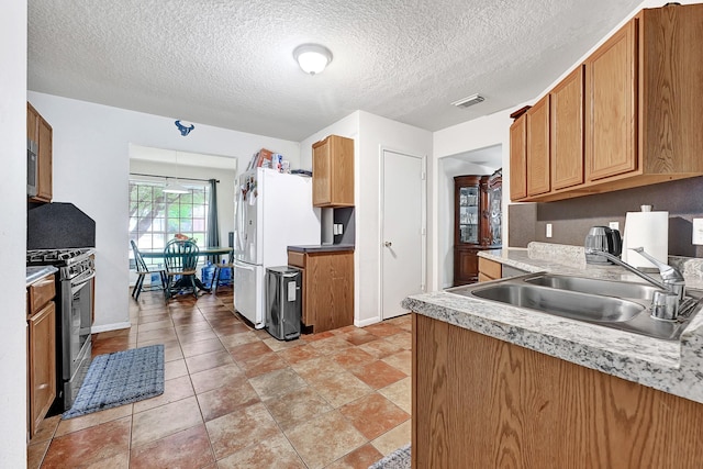 kitchen with stainless steel appliances, light countertops, a sink, visible vents, and a textured ceiling
