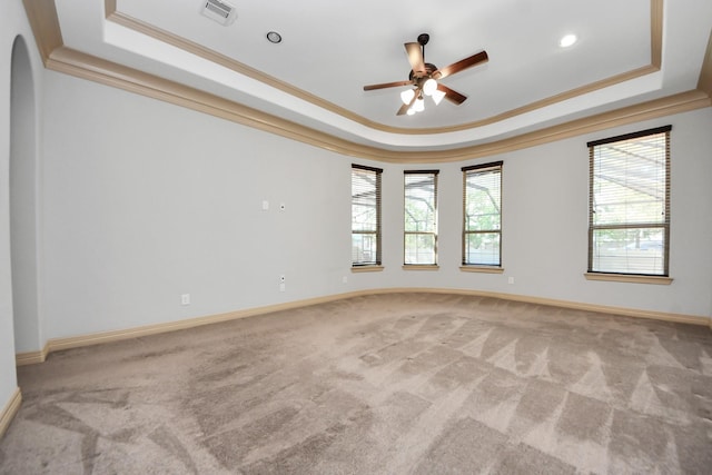 spare room featuring carpet flooring, visible vents, ornamental molding, and a raised ceiling