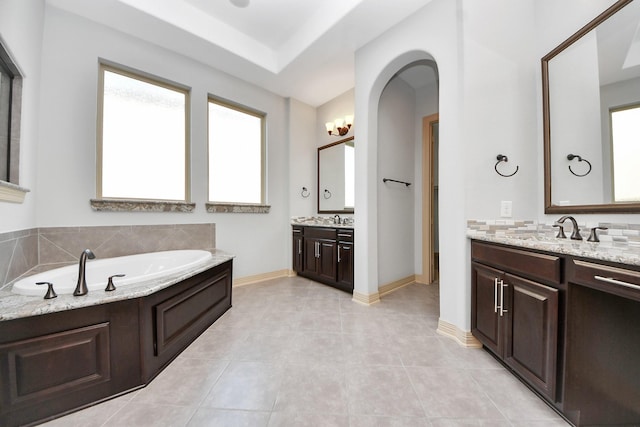 bathroom featuring a sink, tile patterned floors, a garden tub, and two vanities