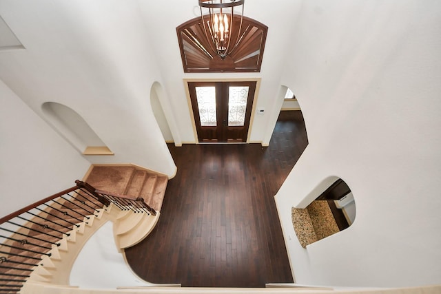 entryway featuring stairs, a chandelier, hardwood / wood-style flooring, and a towering ceiling