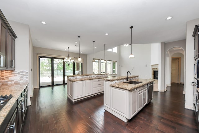 kitchen featuring stainless steel appliances, a center island with sink, a sink, and plenty of natural light