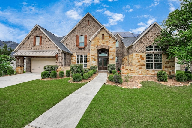 view of front of house with a front lawn, stone siding, french doors, driveway, and solar panels
