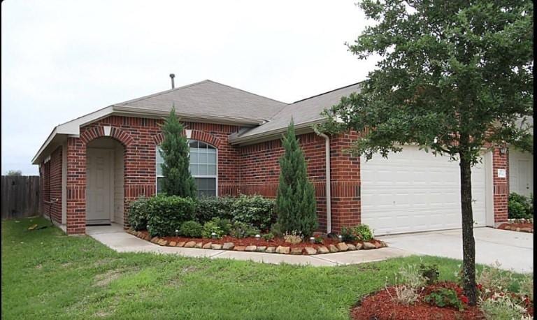 ranch-style home featuring concrete driveway, brick siding, an attached garage, and a front lawn