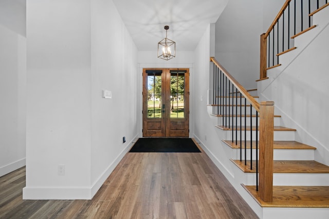 entrance foyer featuring baseboards, stairway, wood finished floors, and an inviting chandelier