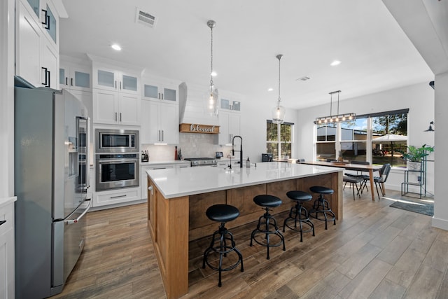 31 Quiet Springs Trl, Willis, TX 77378 - kitchen with appliances with stainless steel finishes, wood finished floors, light countertops, tasteful backsplash, and a breakfast bar area