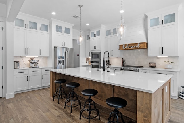 kitchen featuring backsplash, appliances with stainless steel finishes, light wood finished floors, and a sink