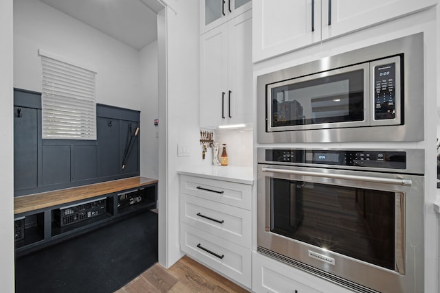 kitchen with wood counters, white cabinetry, glass insert cabinets, appliances with stainless steel finishes, and wood finished floors