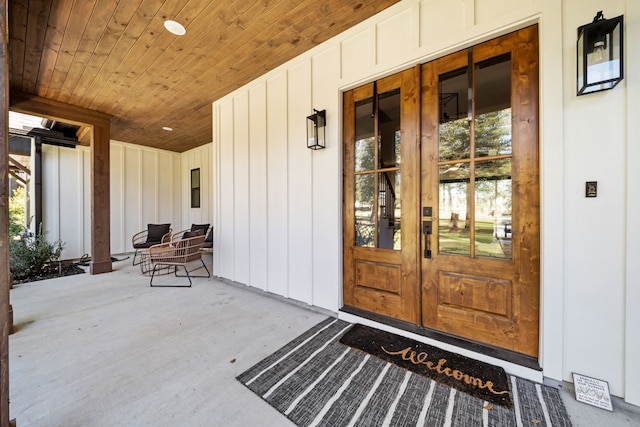 view of exterior entry with french doors, board and batten siding, and a porch