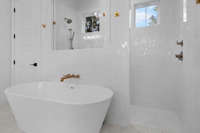 full bathroom with a walk in shower, a freestanding bath, and marble finish floor