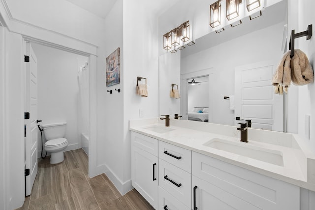 full bathroom featuring toilet, double vanity, a sink, and wood finished floors