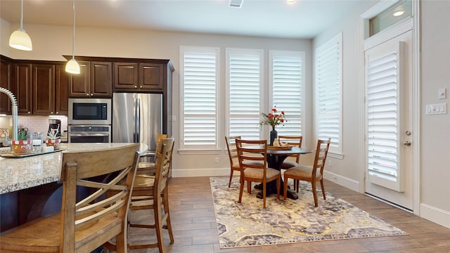 kitchen with baseboards, a breakfast bar area, dark brown cabinets, and stainless steel appliances