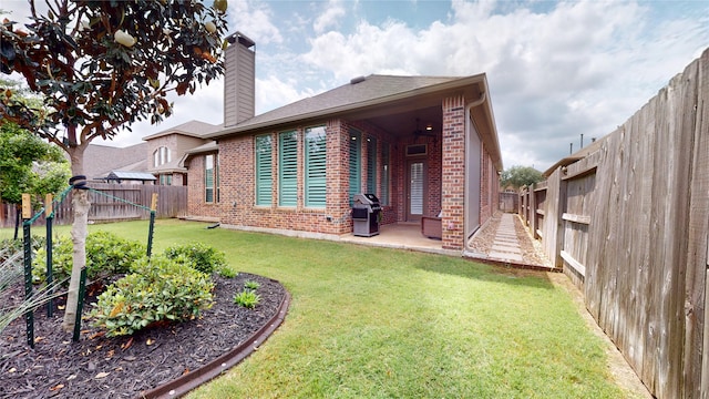 rear view of house with brick siding, a fenced backyard, a chimney, a patio area, and a lawn