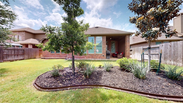 view of front facade featuring a fenced backyard, a patio, a front lawn, and brick siding