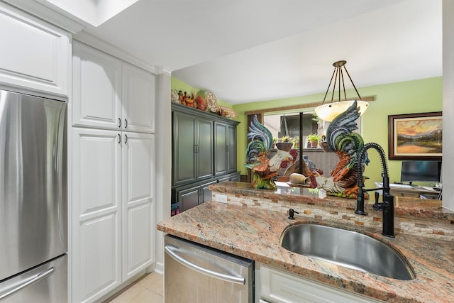 kitchen with white cabinets, light stone counters, a sink, light tile patterned floors, and stainless steel appliances