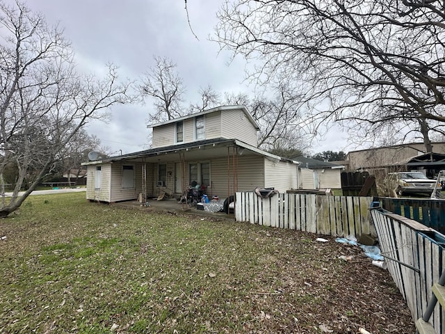 back of property with fence, a patio area, and a lawn
