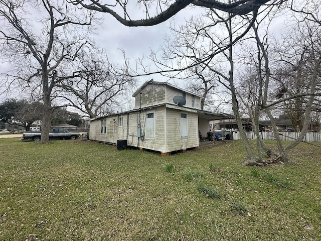 view of side of property featuring fence, central AC unit, and a lawn