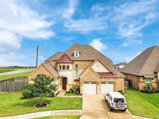 french country home featuring a standing seam roof, driveway, a garage, and fence