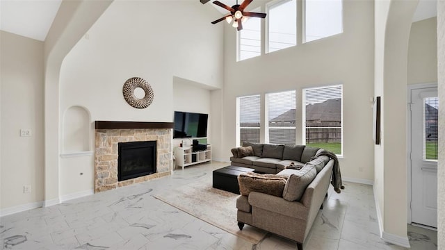 living area featuring ceiling fan, a healthy amount of sunlight, marble finish floor, and a high ceiling
