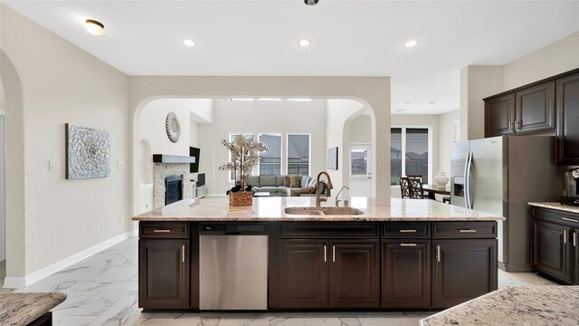 kitchen with stainless steel appliances, marble finish floor, arched walkways, and a sink
