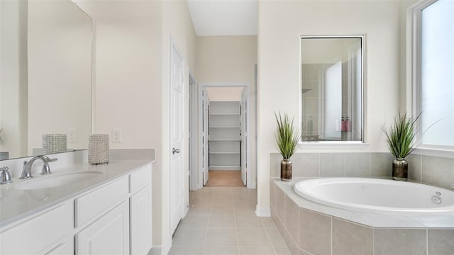 full bathroom featuring tile patterned floors, a walk in closet, a bath, and vanity