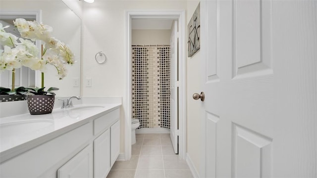 bathroom with curtained shower, a sink, double vanity, toilet, and tile patterned flooring