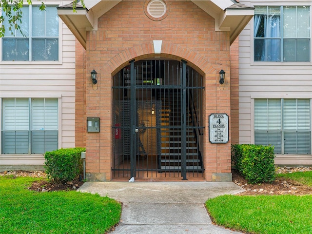 entrance to property featuring a gate and brick siding