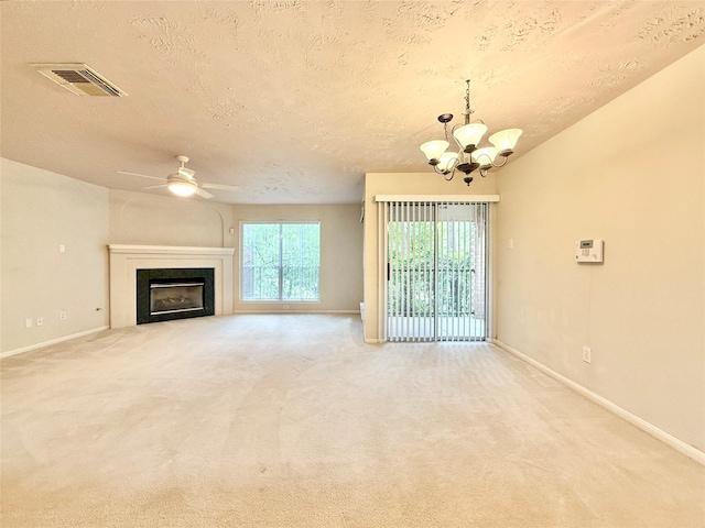 unfurnished living room with a fireplace, a textured ceiling, ceiling fan with notable chandelier, baseboards, and visible vents