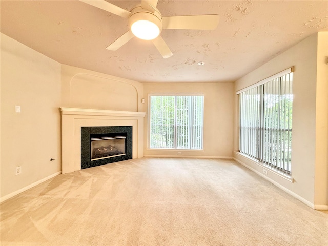 unfurnished living room with a ceiling fan, baseboards, a glass covered fireplace, and carpet
