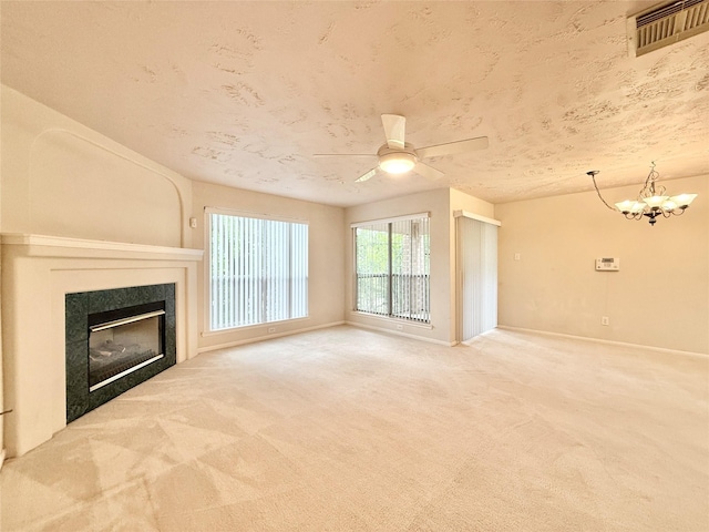 unfurnished living room featuring carpet floors, baseboards, ceiling fan with notable chandelier, and visible vents