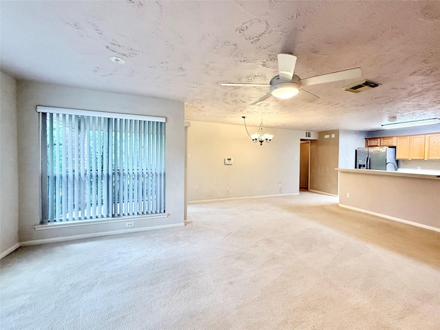 unfurnished living room with baseboards, light carpet, and ceiling fan with notable chandelier