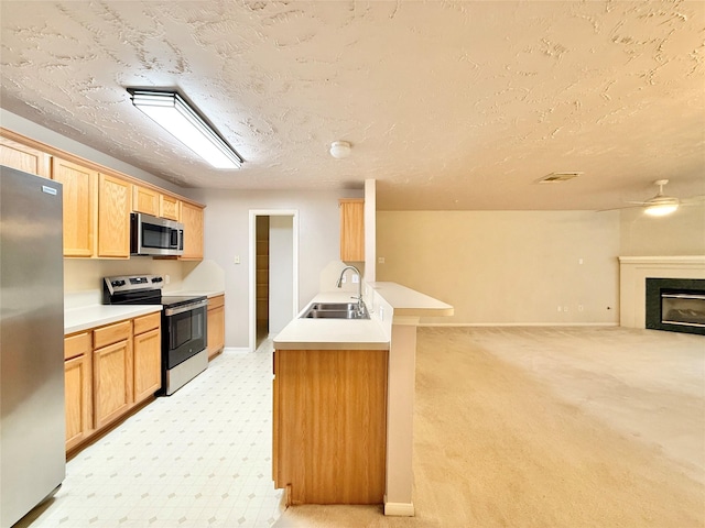 kitchen with light carpet, open floor plan, a textured ceiling, a sink, and stainless steel appliances