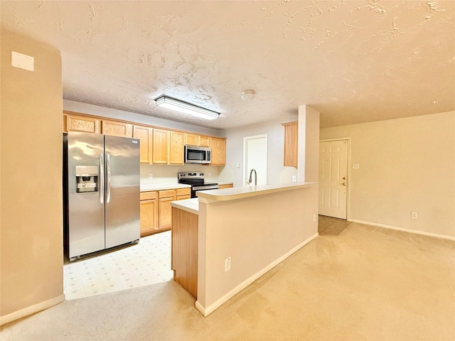 kitchen with a peninsula, light brown cabinets, baseboards, light colored carpet, and stainless steel appliances